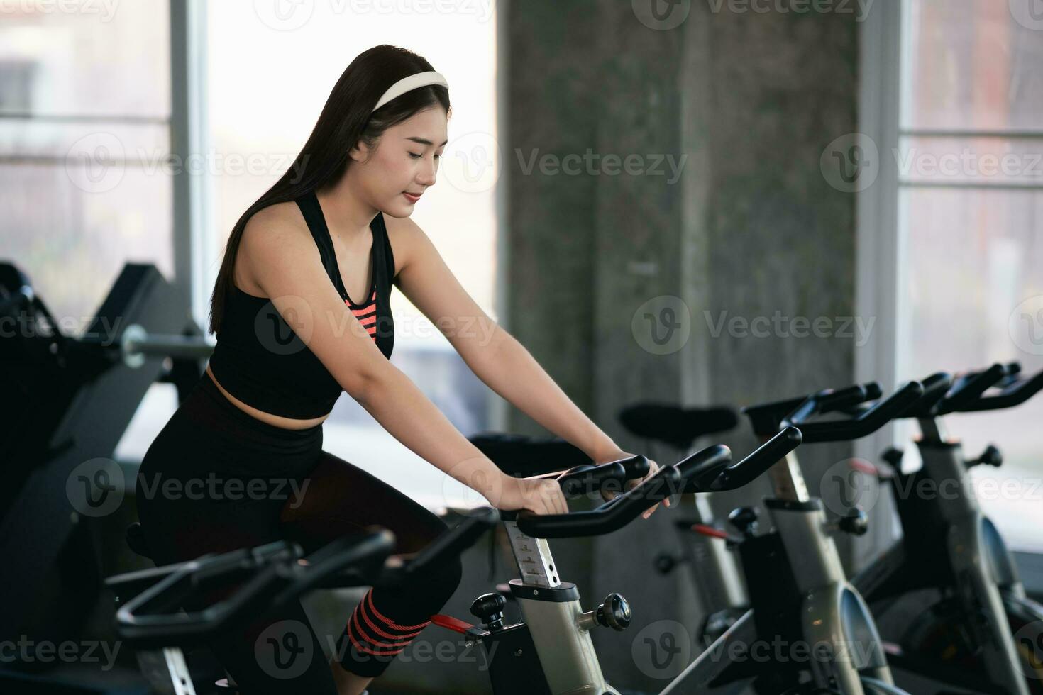 asiatische Sportlerin, die im Fitnessstudio auf einem Fahrrad trainiert, Entschlossenheit, Gewicht zu verlieren, macht sie gesund. Heimtrainer Frau Fitness Sportkonzept. foto