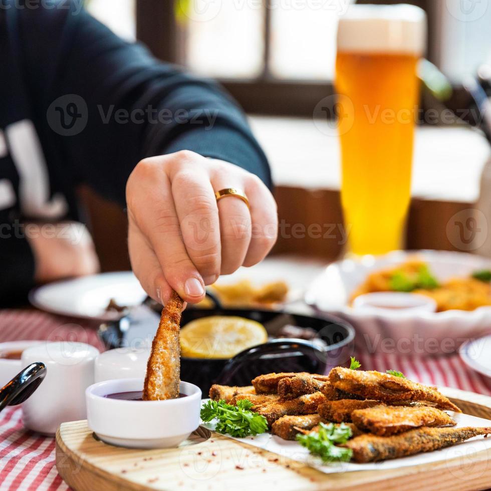 Mann taucht Kilka ein, sprot Fisch in Ketchup Nahaufnahme foto