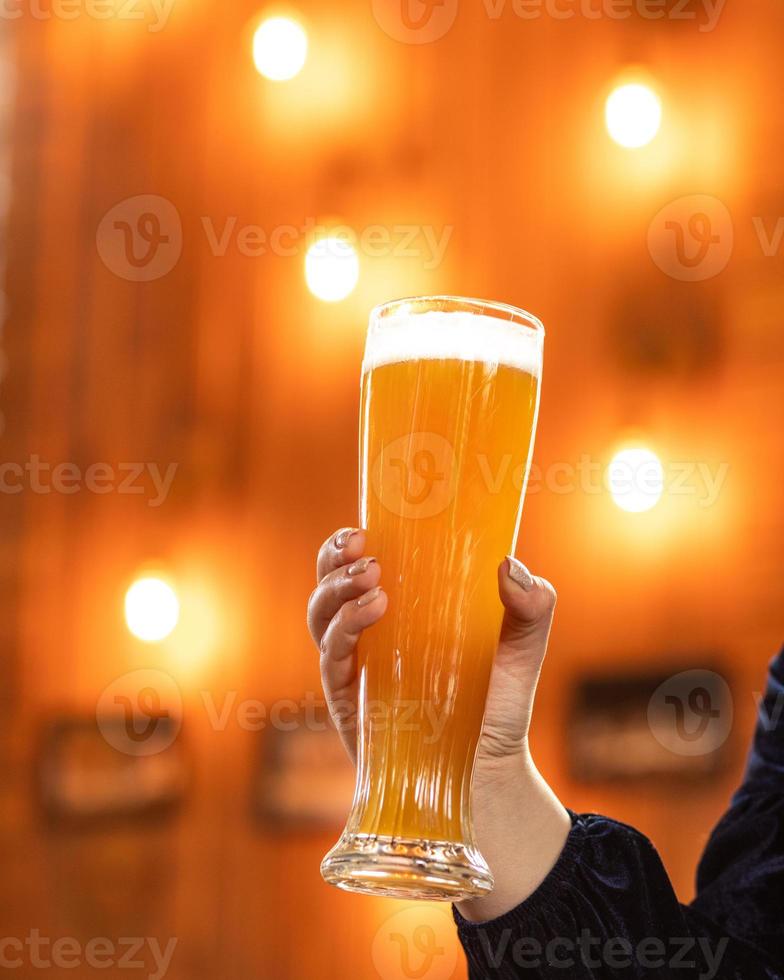 Frau, die Bierkrug am Restaurant mit Bokehhintergrund hält foto