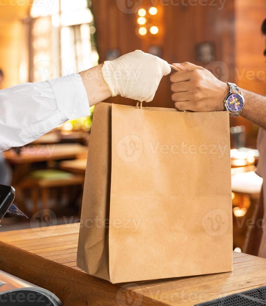 Arbeiter, der dem Kunden einen Beutel mit der Bestellung von Fertiggerichten gibt foto