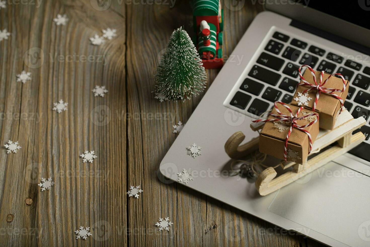 klein hölzern Schlitten mit Weihnachten die Geschenke auf ein Laptop. foto