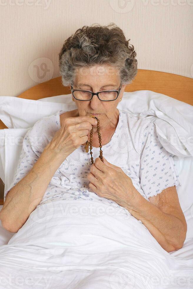 alt Frau ist beten im das Bett foto
