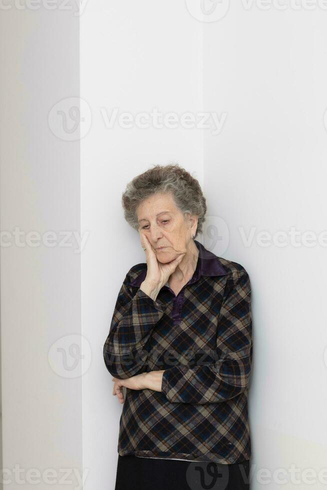 alt Frau von 80 Jahre alt bleibt schließen zu das Fenster foto
