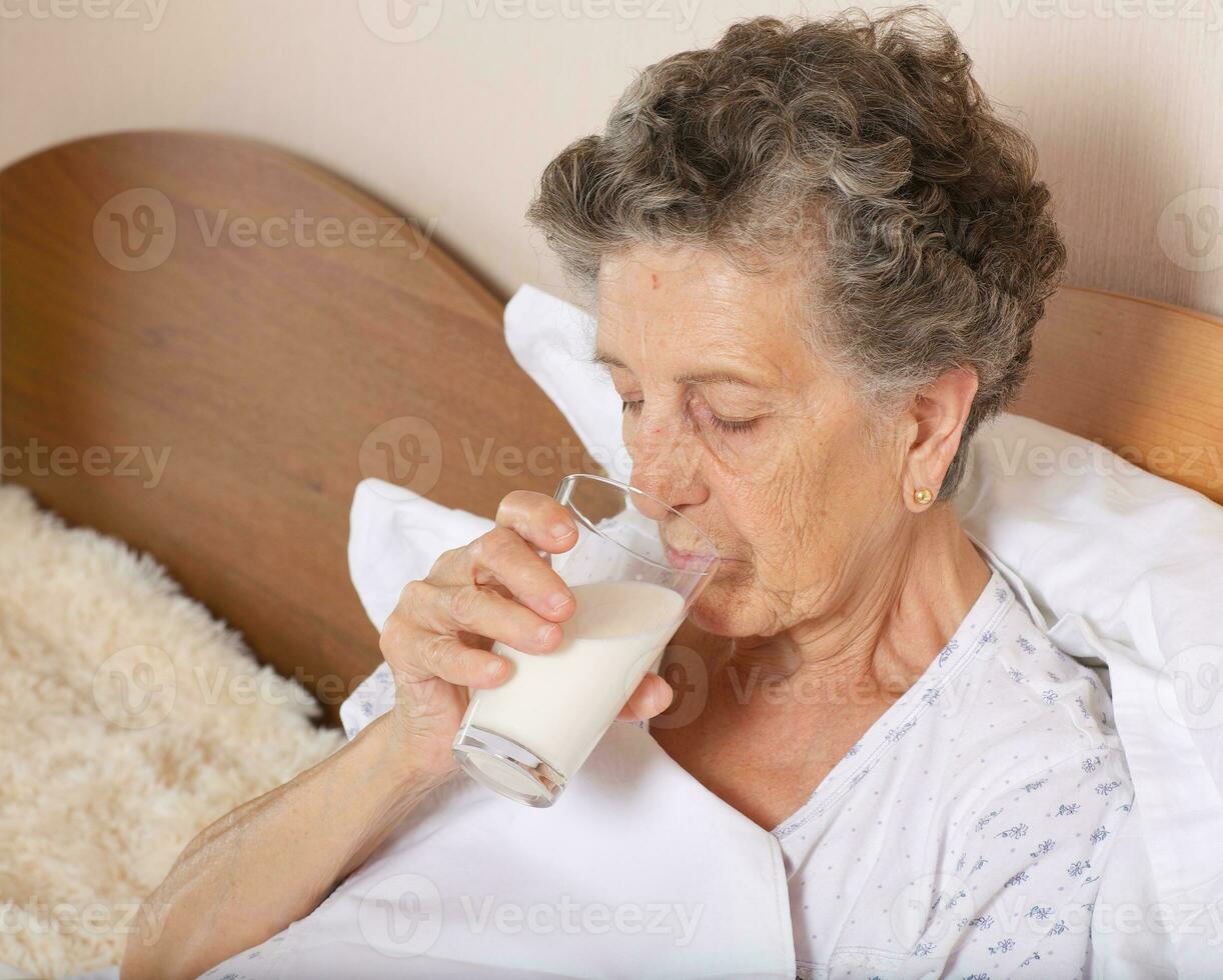 alt Frau Getränke etwas Milch im das Morgen foto