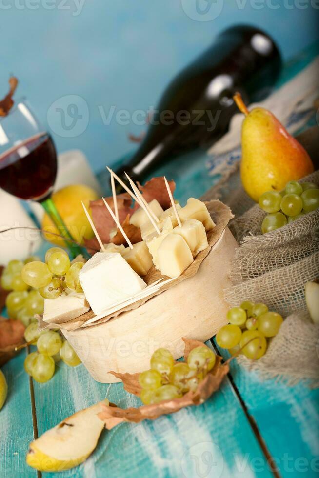 Käse Scheiben, Birne, und Trauben auf ein hölzern Stand. foto