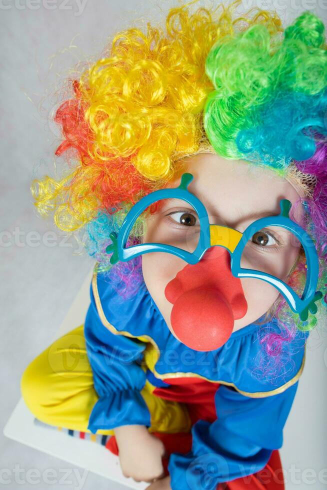 Junge von fünf Jahre gekleidet im das Kostüm von ein Clown und komisch Brille mit rot Nase. foto