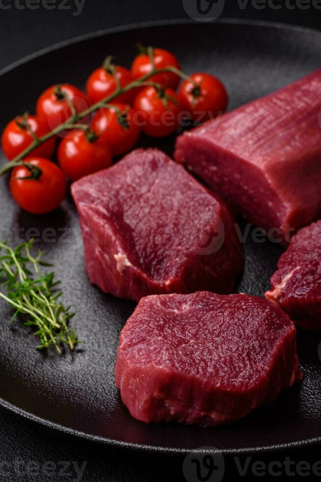 saftig roh Rindfleisch mit Gewürze, Salz- und Kräuter auf ein dunkel Beton Hintergrund foto