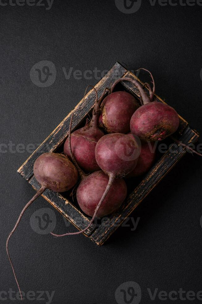 frisch roh Rote Beete im das bilden von Knollen auf ein texturiert Beton Hintergrund foto