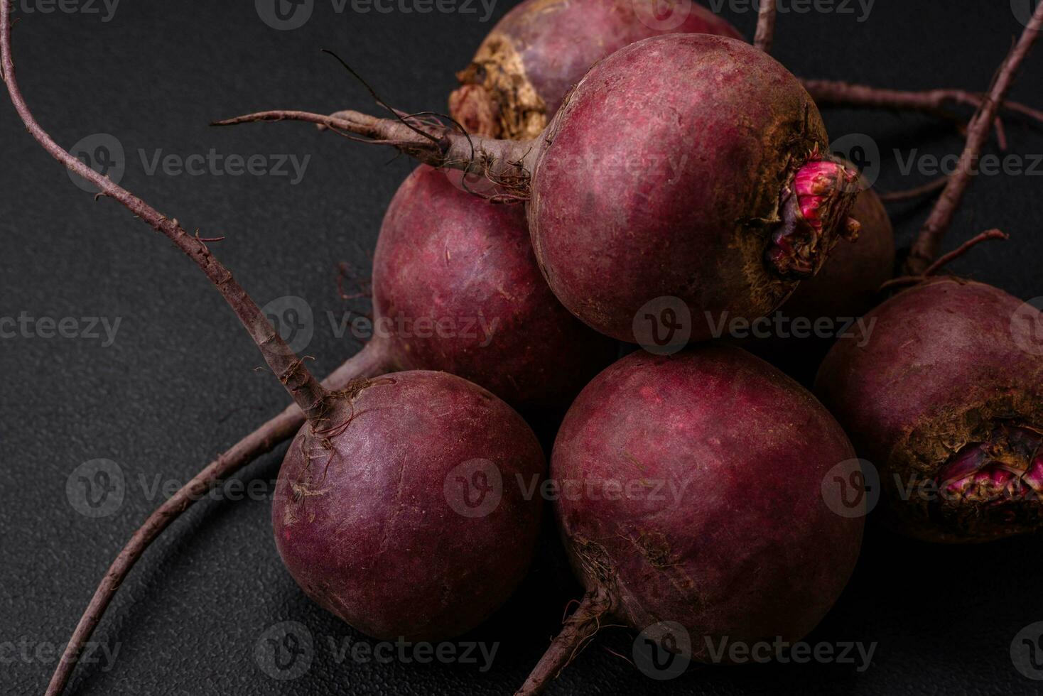 frisch roh Rote Beete im das bilden von Knollen auf ein texturiert Beton Hintergrund foto