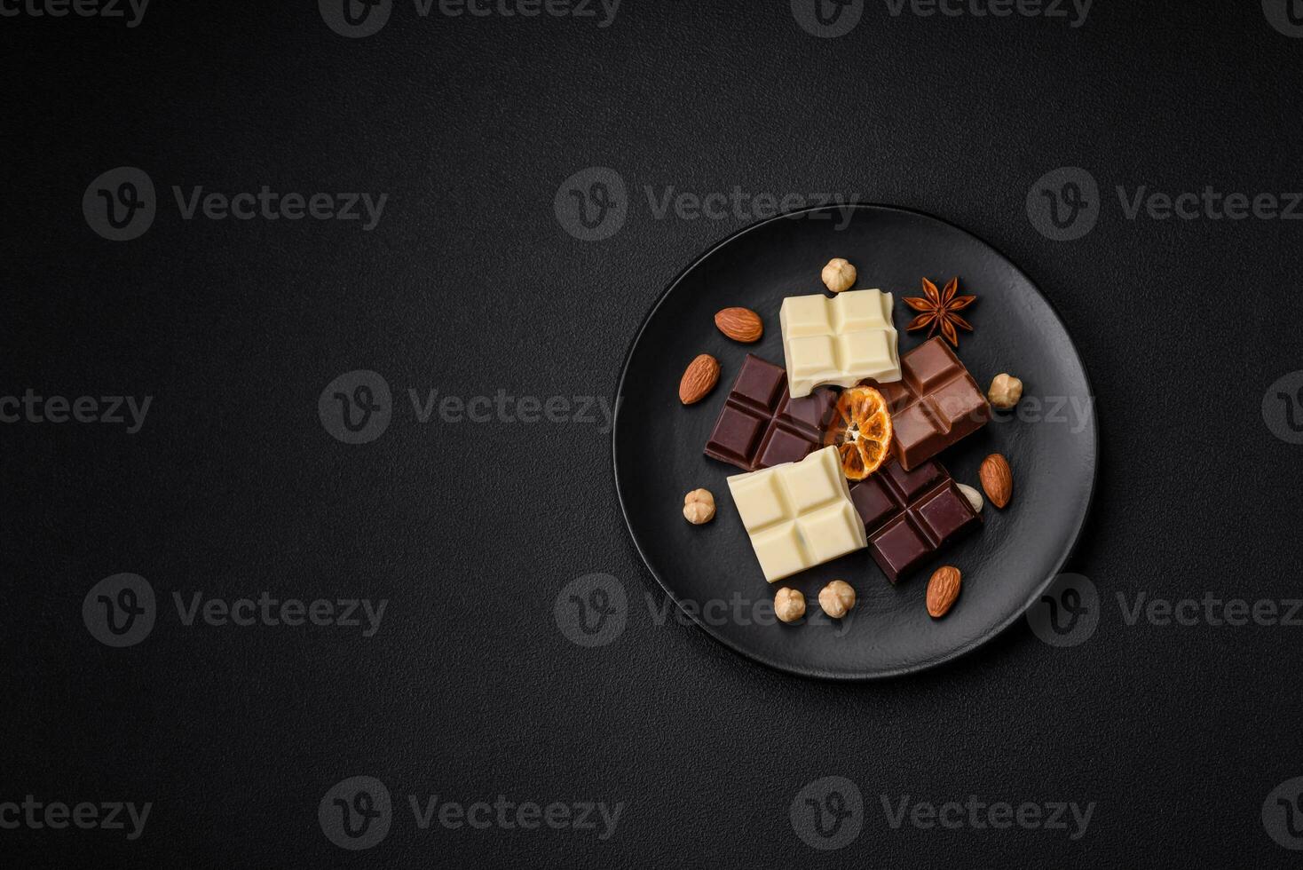 ein mischen von mehrere Typen von köstlich Süss Schokolade gebrochen in Würfel auf ein schwarz Teller foto