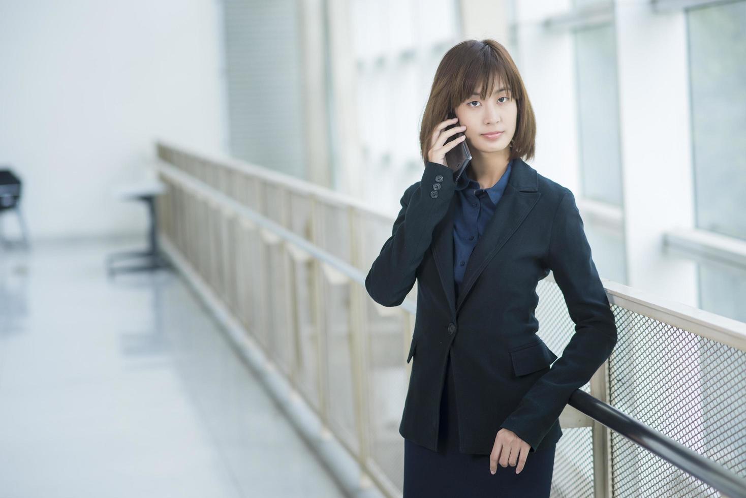 attraktive asiatische Geschäftsfrau, die auf Smartphone außerhalb des Büros verwendet foto
