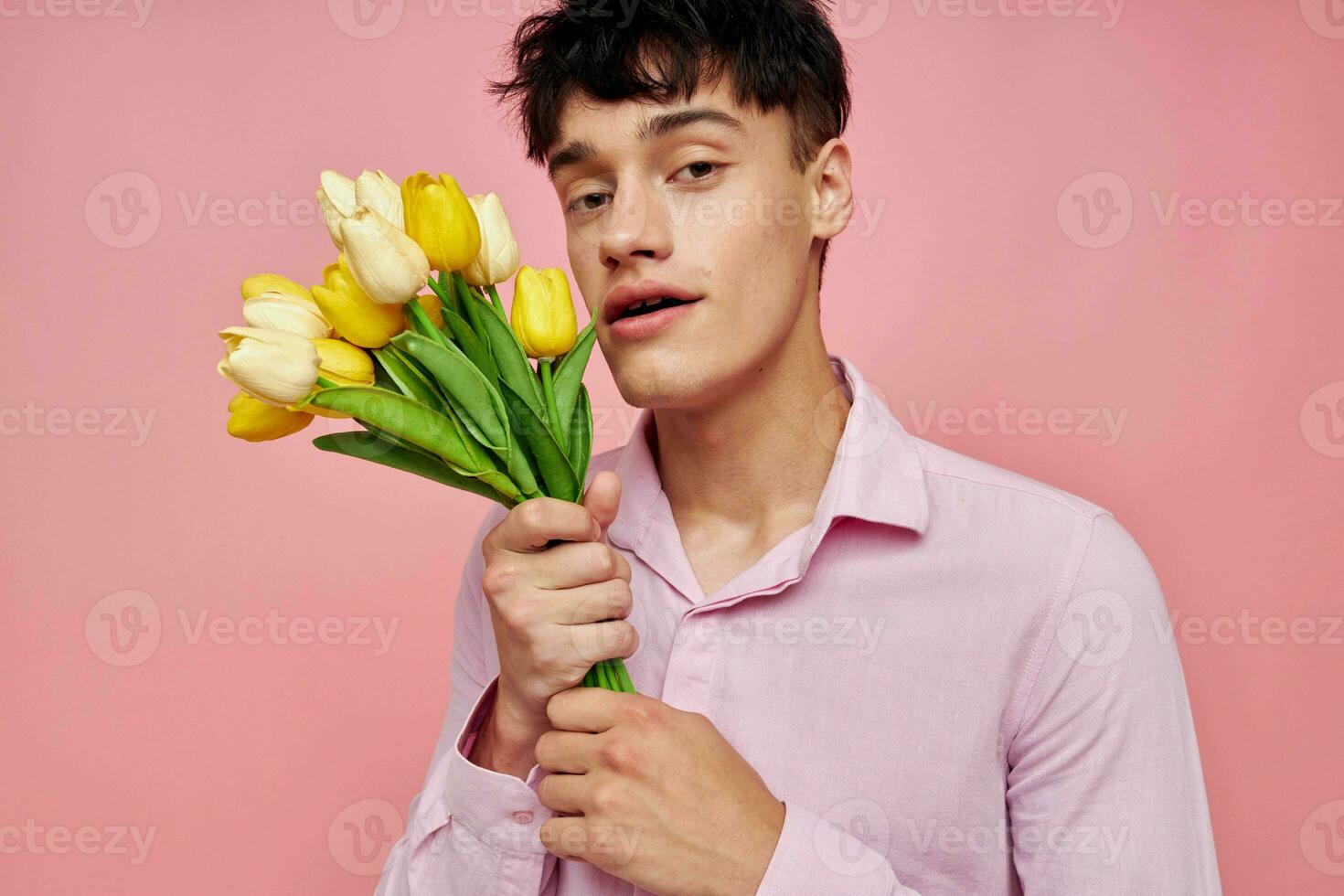 Porträt von ein jung Mann im ein Rosa Hemd mit ein Strauß von Blumen gestikulieren mit seine Hände Lebensstil unverändert foto