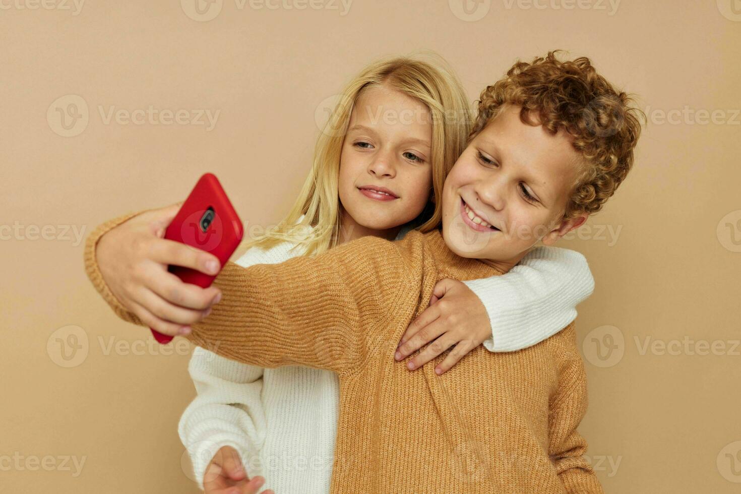 wenig Junge und Mädchen mit ein rot Telefon zusammen Technologien isoliert Hintergrund foto