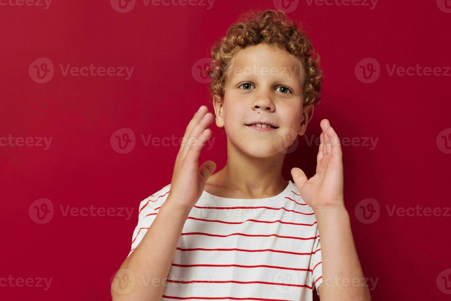 süß Junge mit lockig Haar im gestreift T-Shirt Emotionen foto