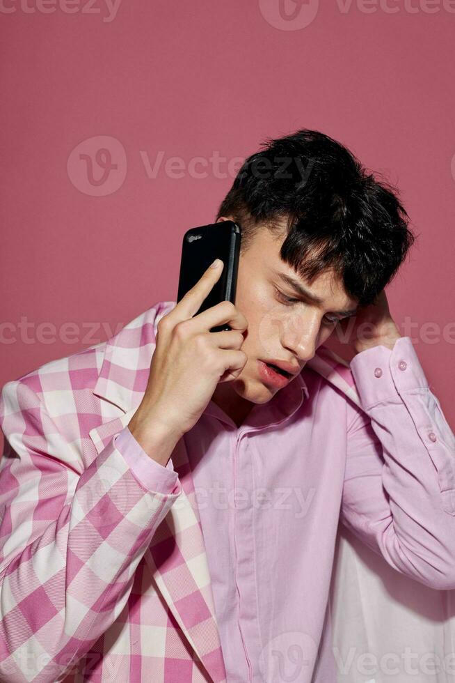 gut aussehend Kerl mit ein Telefon im Hand Rosa Blazer Mode elegant Stil Modell- Studio foto