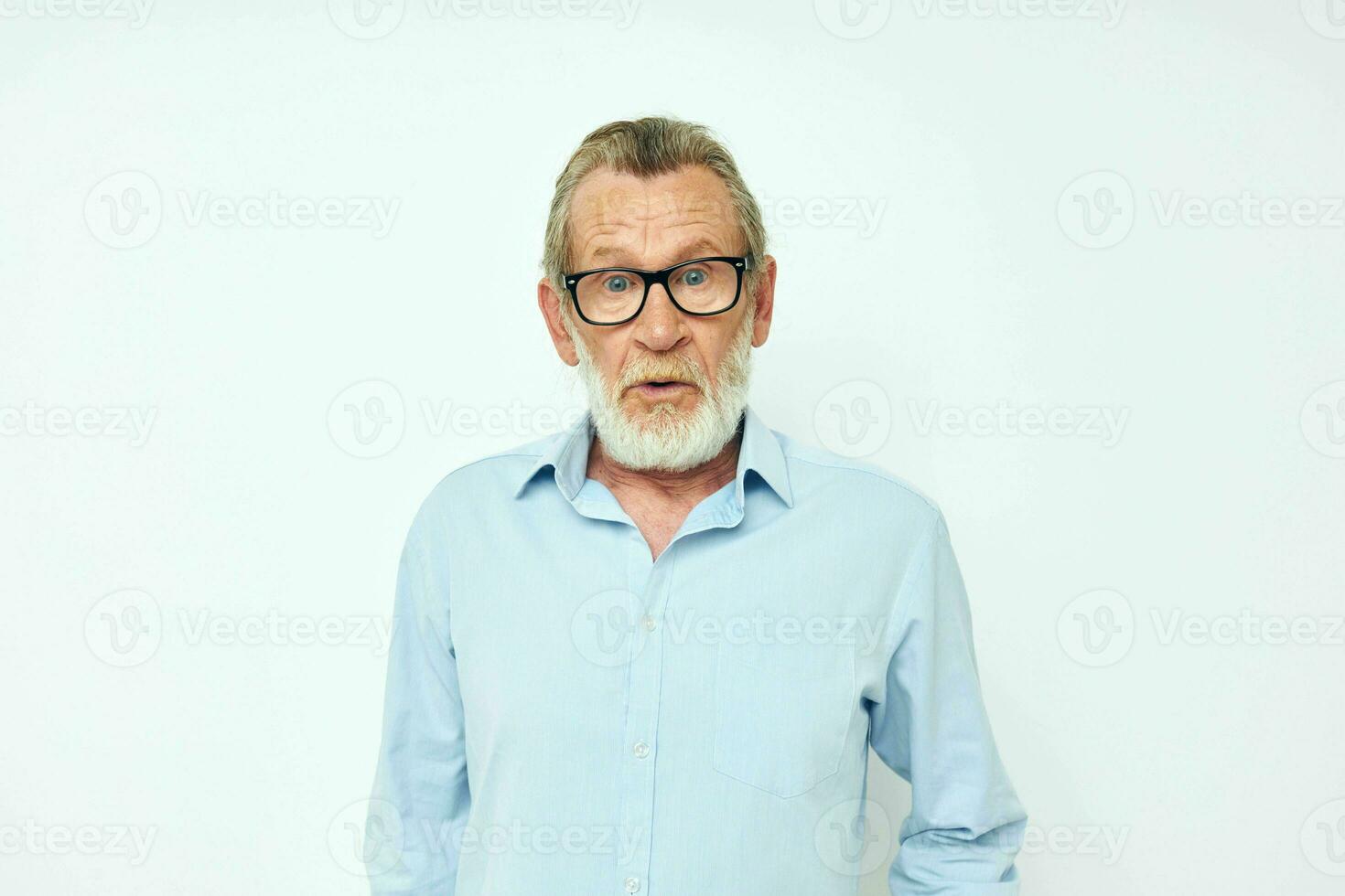 Senior grauhaarig Mann im Blau Hemden Gesten mit seine Hände Licht Hintergrund foto