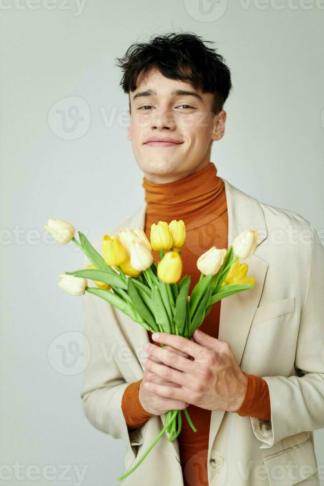 ein jung Mann im Weiß Jacke mit ein Strauß von Gelb Blumen elegant Stil Rosa Hintergrund unverändert foto