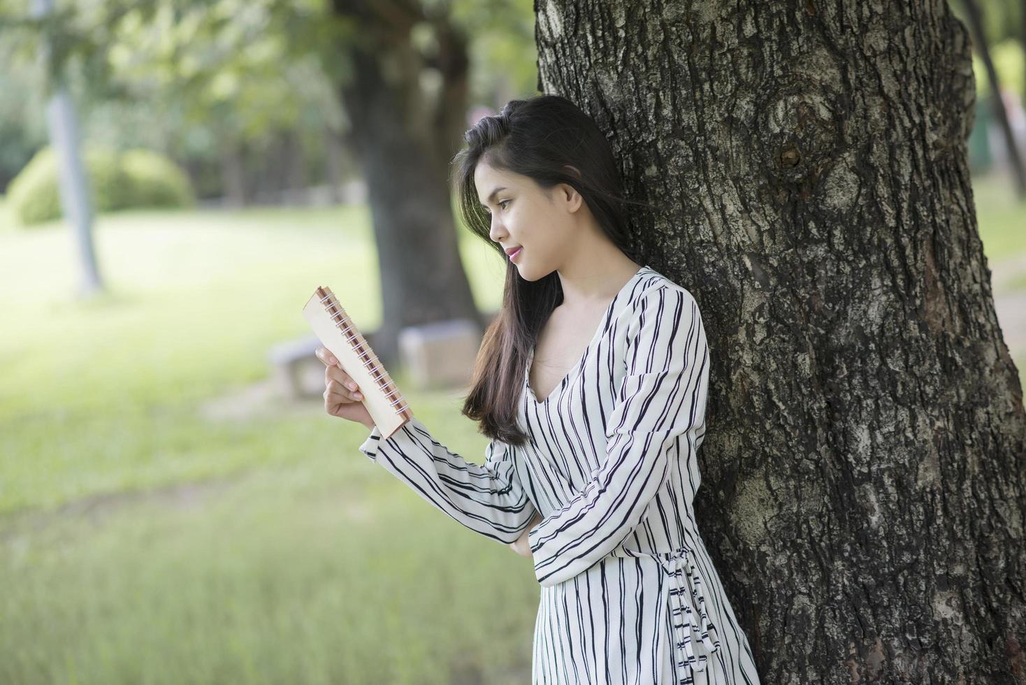 attraktive Frau, die ein Buch im Park liest foto