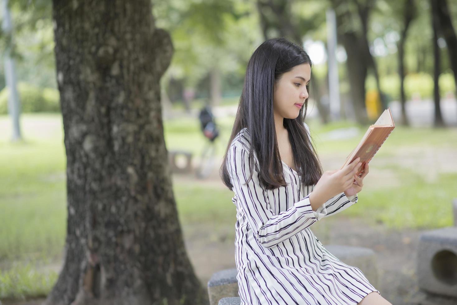 attraktive Frau, die ein Buch im Park liest foto