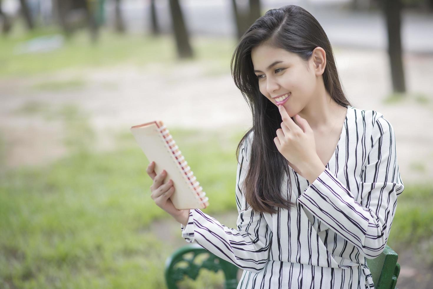 attraktive Frau, die ein Buch im Park liest foto