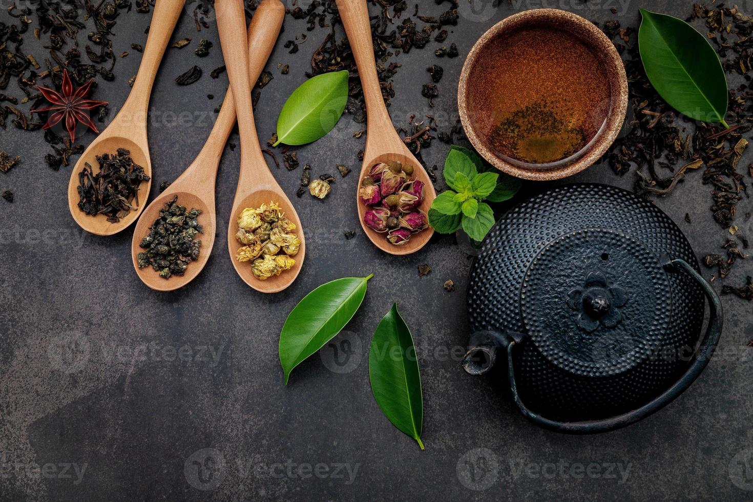 Teekanne aus schwarzem Gusseisen mit Kräutertee auf dunklem Steinhintergrund foto