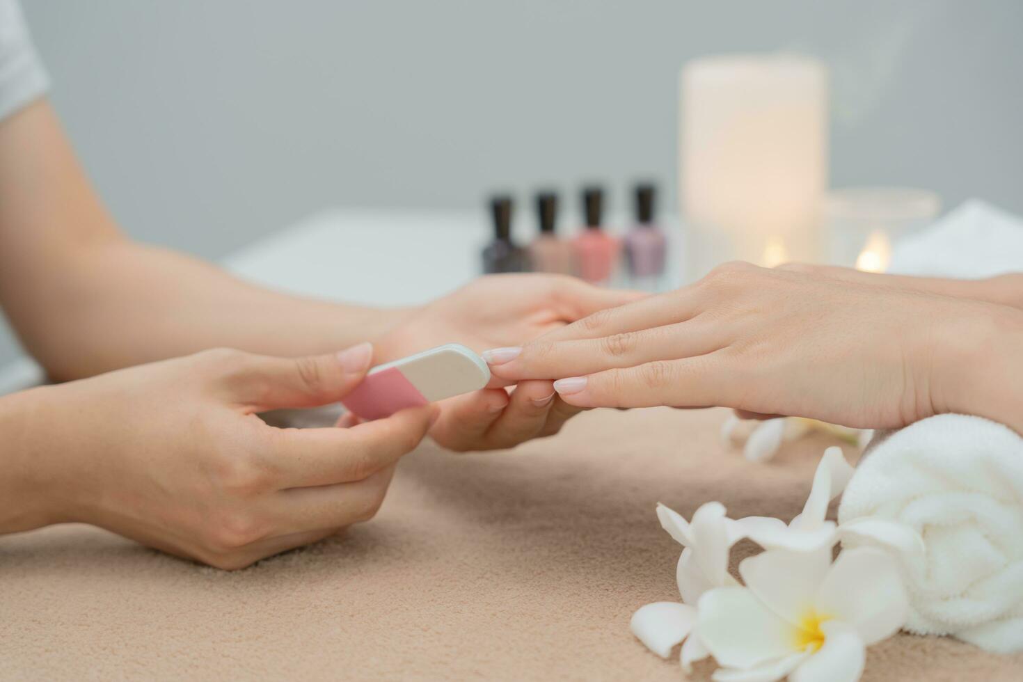 frau wird von einer professionellen kosmetikerin maniküre im spa-zentrum betreut. nagelschönheitssalon verwenden nagelfeile für die glasurbehandlung. Maniküre machen Nagelkunden schön. Spa-Behandlung für die Körperpflege foto