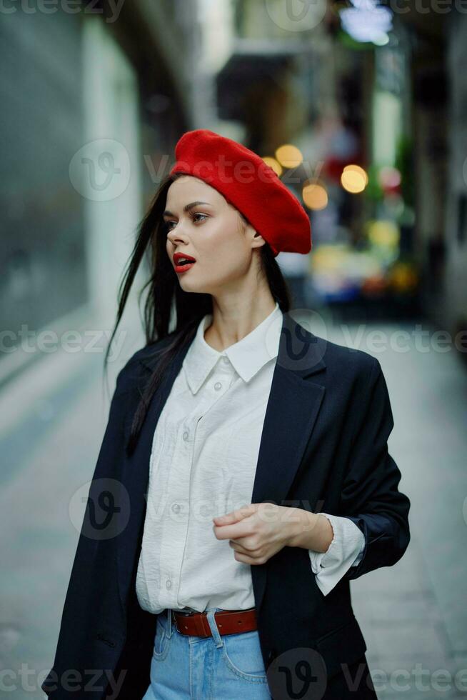 Mode Frau Lächeln mit Zähne Porträt Gehen Tourist im stilvoll Kleider im Jacke mit rot Lippen Gehen Nieder eng Stadt Straße fliegend Haar, reisen, filmisch Farbe, retro Jahrgang Stil. foto