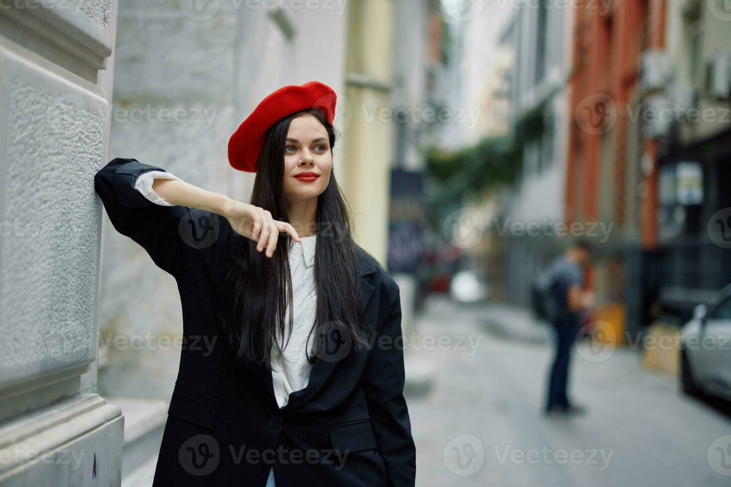 Frau Stehen in der Nähe von ein Mauer im das Stadt tragen ein stilvoll Jacke und rot Baskenmütze mit rot Lippen, Reise und Freizeit, Französisch Stil von Kleid. foto