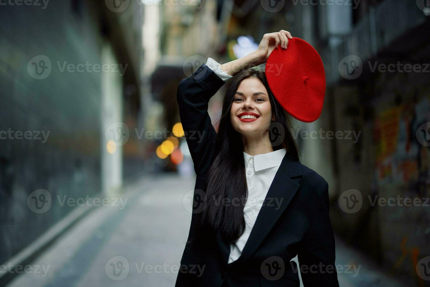 Mode Frau Lächeln mit Zähne und Spaß Tourist im stilvoll Kleider im Jacke und rot Baskenmütze Gehen Nieder eng Stadt Straße fliegend Haar, reisen, Französisch Stil, filmisch Farbe, retro Stil. foto