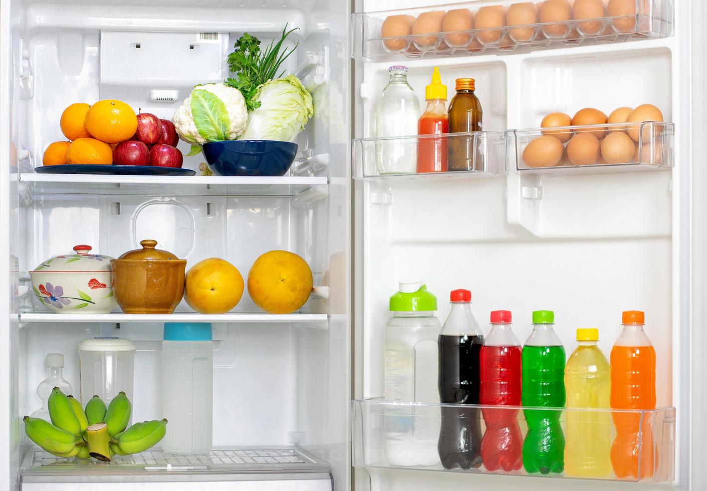 Kühlschrank mit offener Tür mit vielen frischen Speisen und Getränken foto
