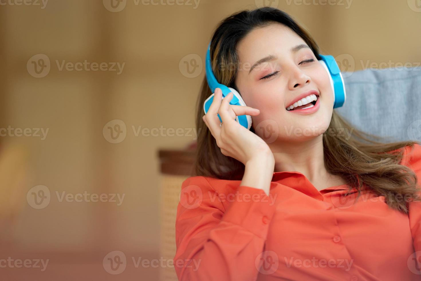 Porträt der jungen schönen Frau, die die Musik mit dem Smileygesicht genießt, das im kreativen Büro oder im Café sitzt foto