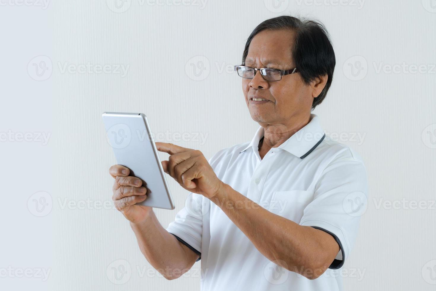 Porträt des asiatischen älteren Mannes unter Verwendung einer digitalen Tablette foto