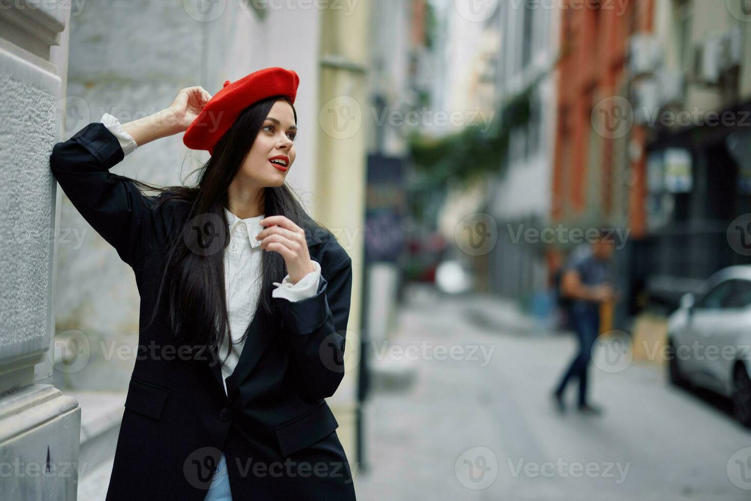 ein Frau Stehen in der Nähe von ein Mauer im das Stadt tragen ein stilvoll Jacke und ein rot Baskenmütze mit rot Lippen, reisen. foto