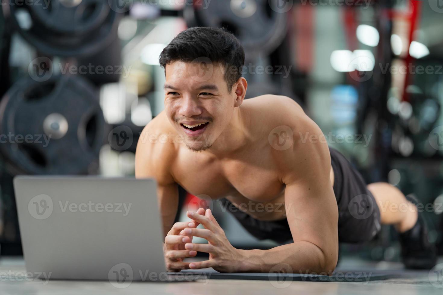 Online-Training Sportmann Training macht Liegestütze Übung mit Laptop im Fitnessstudio foto