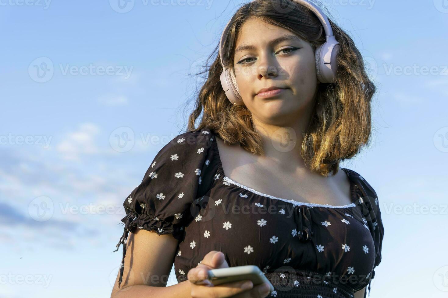 Teenager Mädchen im ein Kleid hört zu zu Musik- auf ihr Smartphone foto