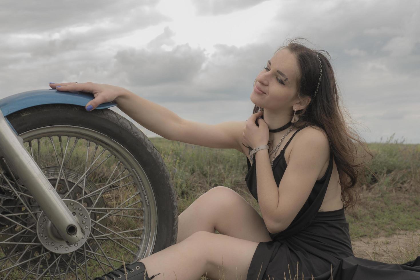 brünette Biker auf einem Motorrad im Lavendelfeld gegen den Himmel mit Wolkenzeitlupe foto