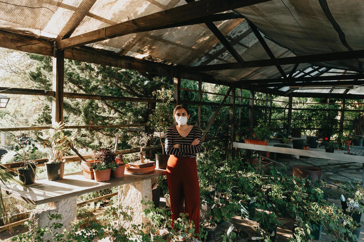 eine Frau, die eine Maske trägt und Gartenarbeit macht foto