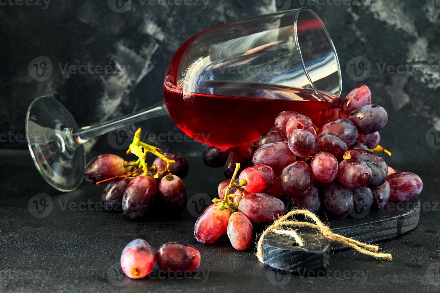 Glas Wein mit Trauben auf einem schwarzen Holzständer foto