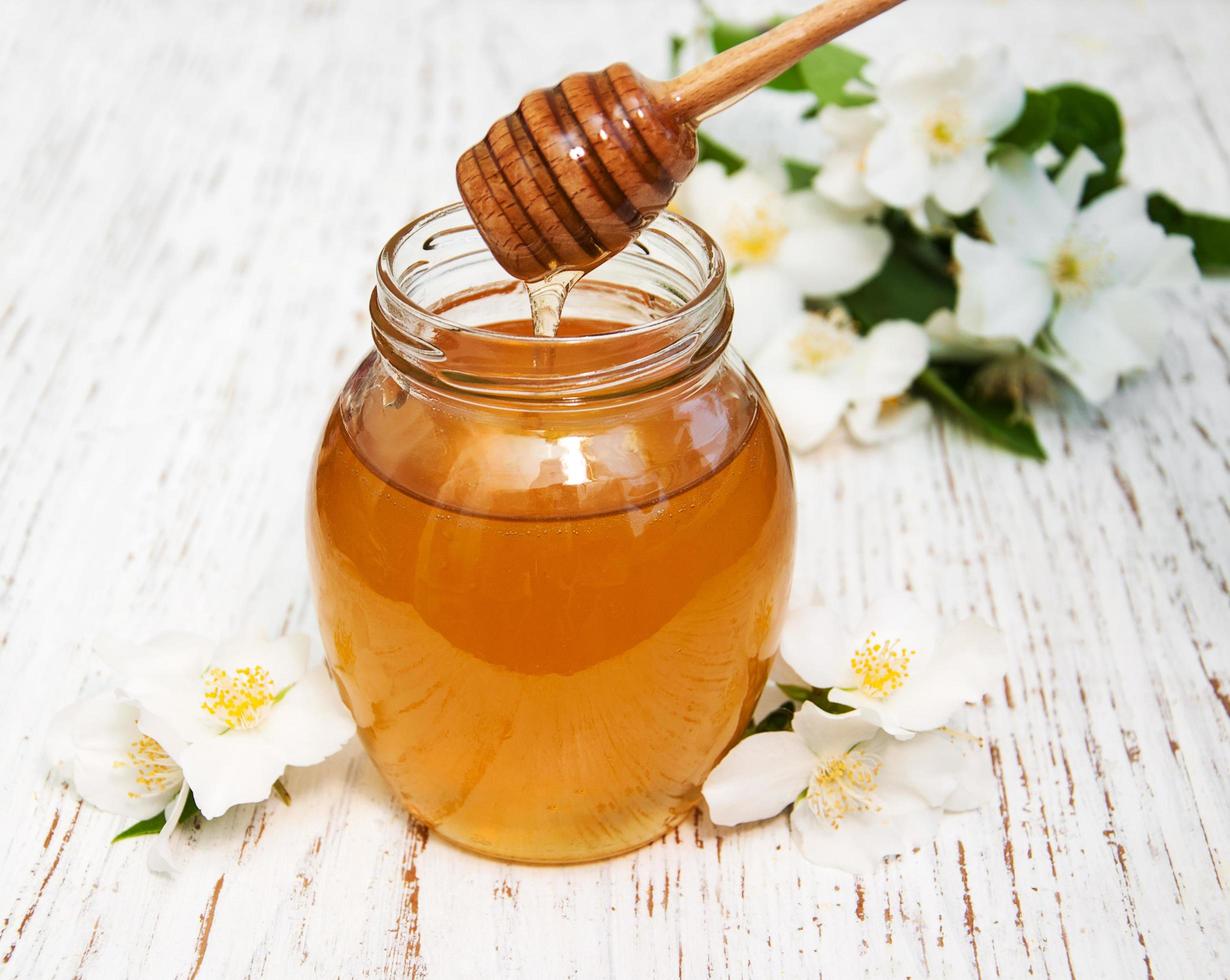Honig mit Jasminblüten auf einem hölzernen Hintergrund foto