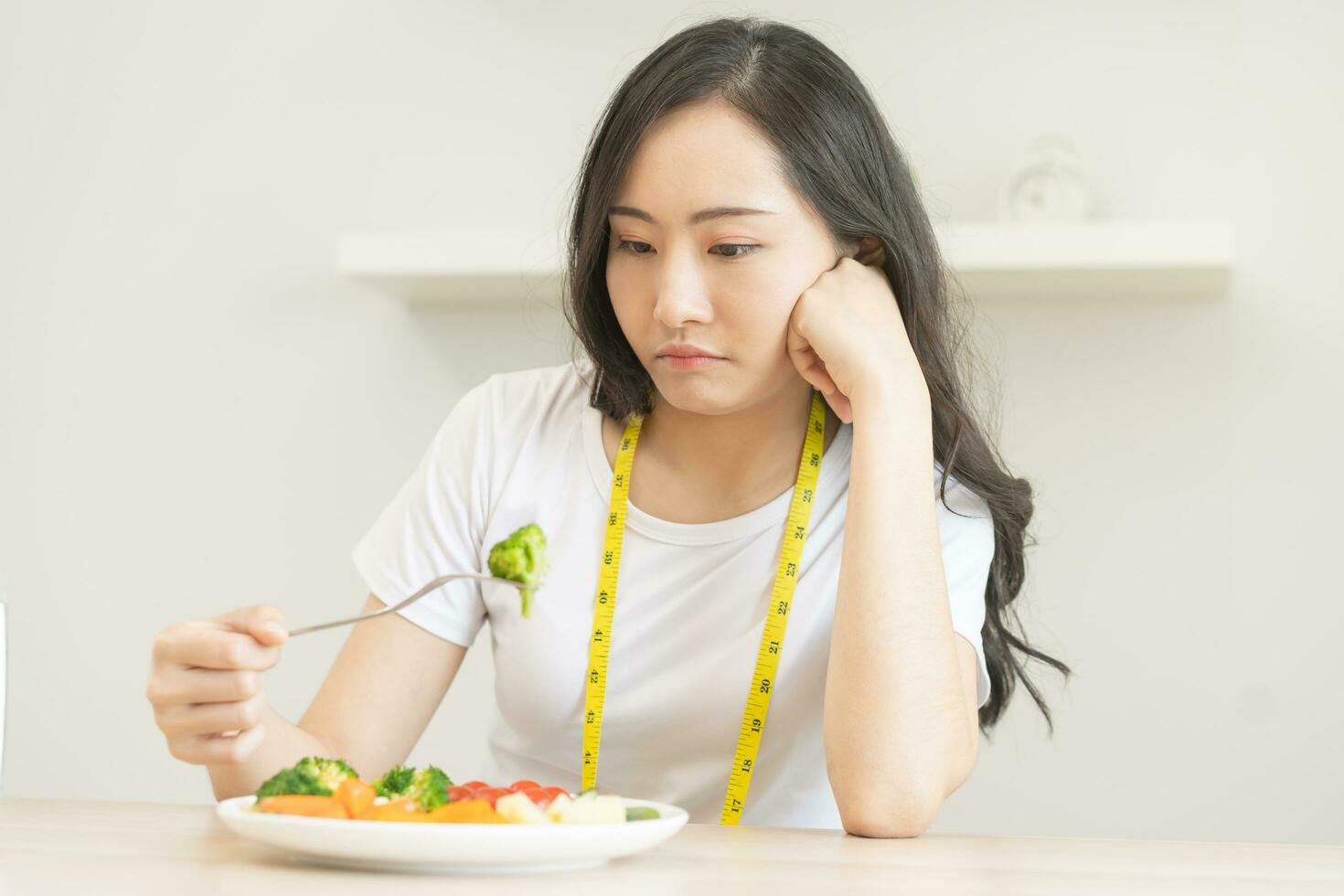 Diät im gelangweilt. Nahansicht Brokkoli unzufrieden schön asiatisch jung Frau, Mädchen auf Diät, Hand halten Gabel im Salat Platte, nicht gefallen oder müde mit Essen frisch Gemüse. Ernährung von gesund Essen gut Geschmack foto