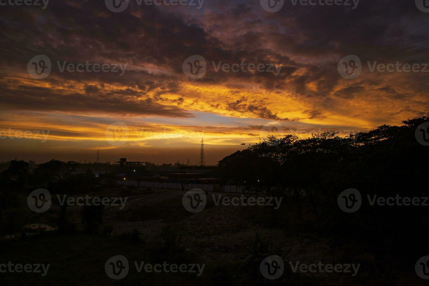 Sonnenuntergang Über das Stadt, Silhouette von ein hoch Stromspannung Getriebe Turm foto