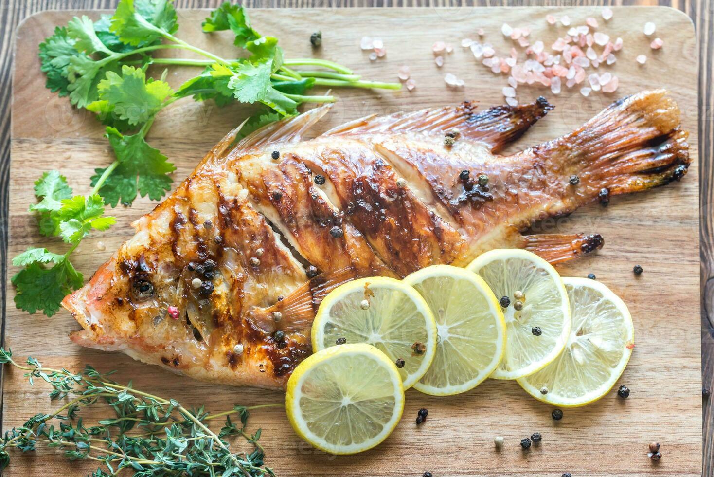 gegrillt Tilapia mit Kräuter auf das hölzern Tafel foto