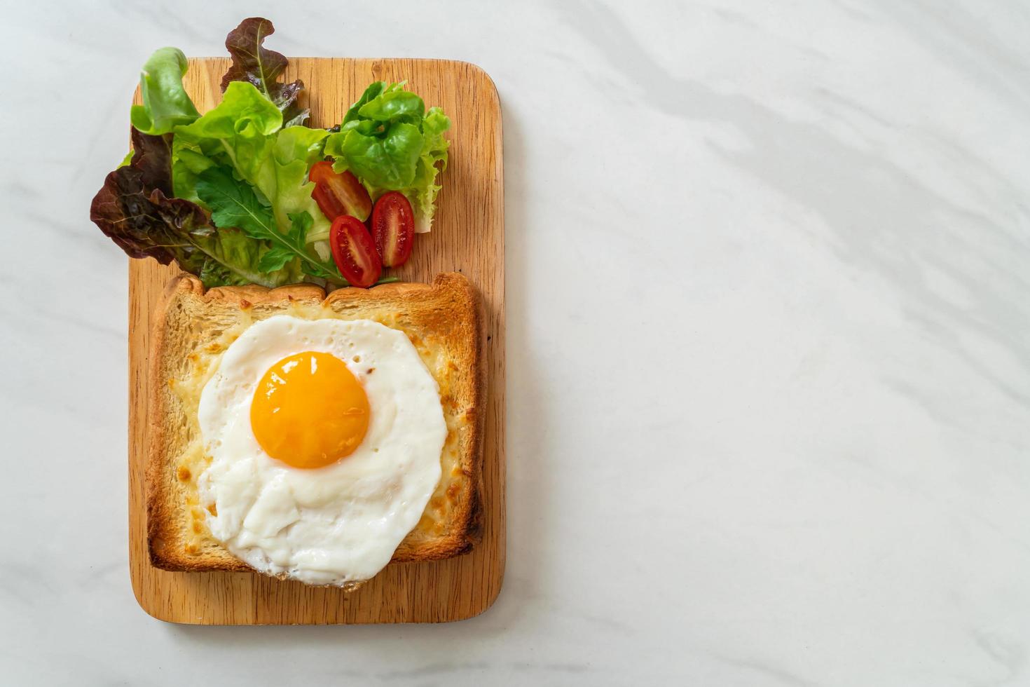 hausgemachtes Brot geröstet mit Käse und Spiegelei obenauf mit Gemüsesalat zum Frühstück foto