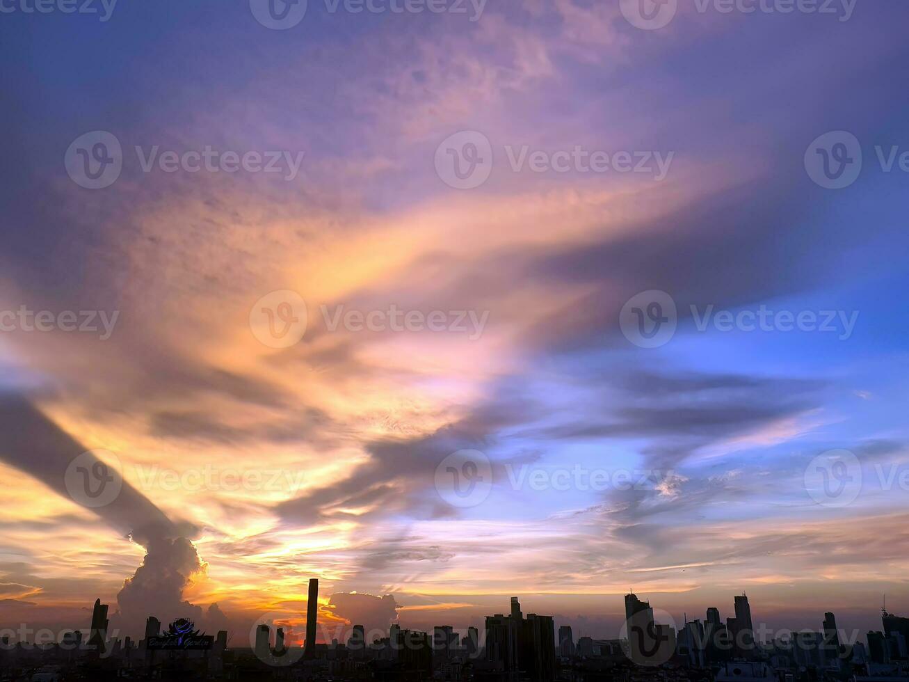 Sonnenuntergang im das Abend mit dramatisch gestalten und Farbe von Wolken und Himmel mit Silhouette von Stadtbild, Gebäude Horizont, Wolkengebilde, Natur Hintergrund foto