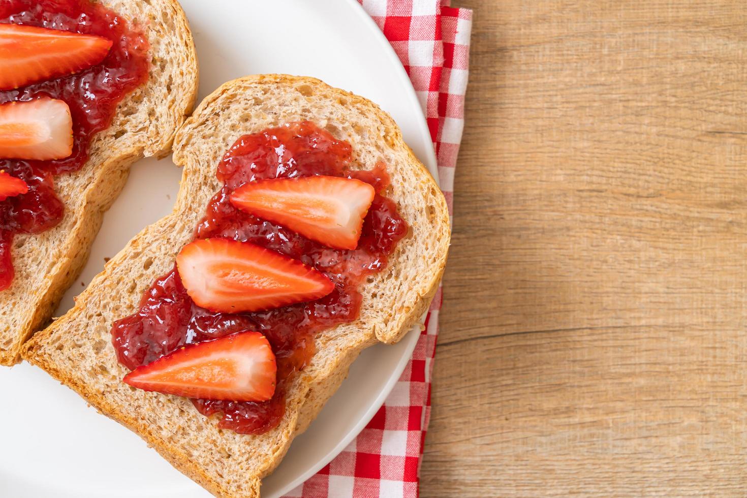 hausgemachtes Vollkornbrot mit Erdbeermarmelade und frischen Erdbeeren foto