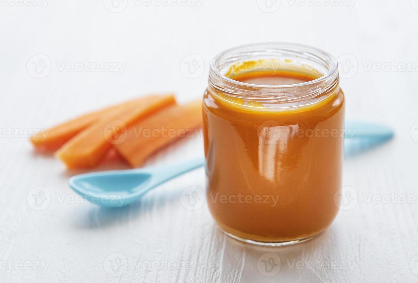 Baby-Karotte mit Löffel im Glas zerdrückt foto