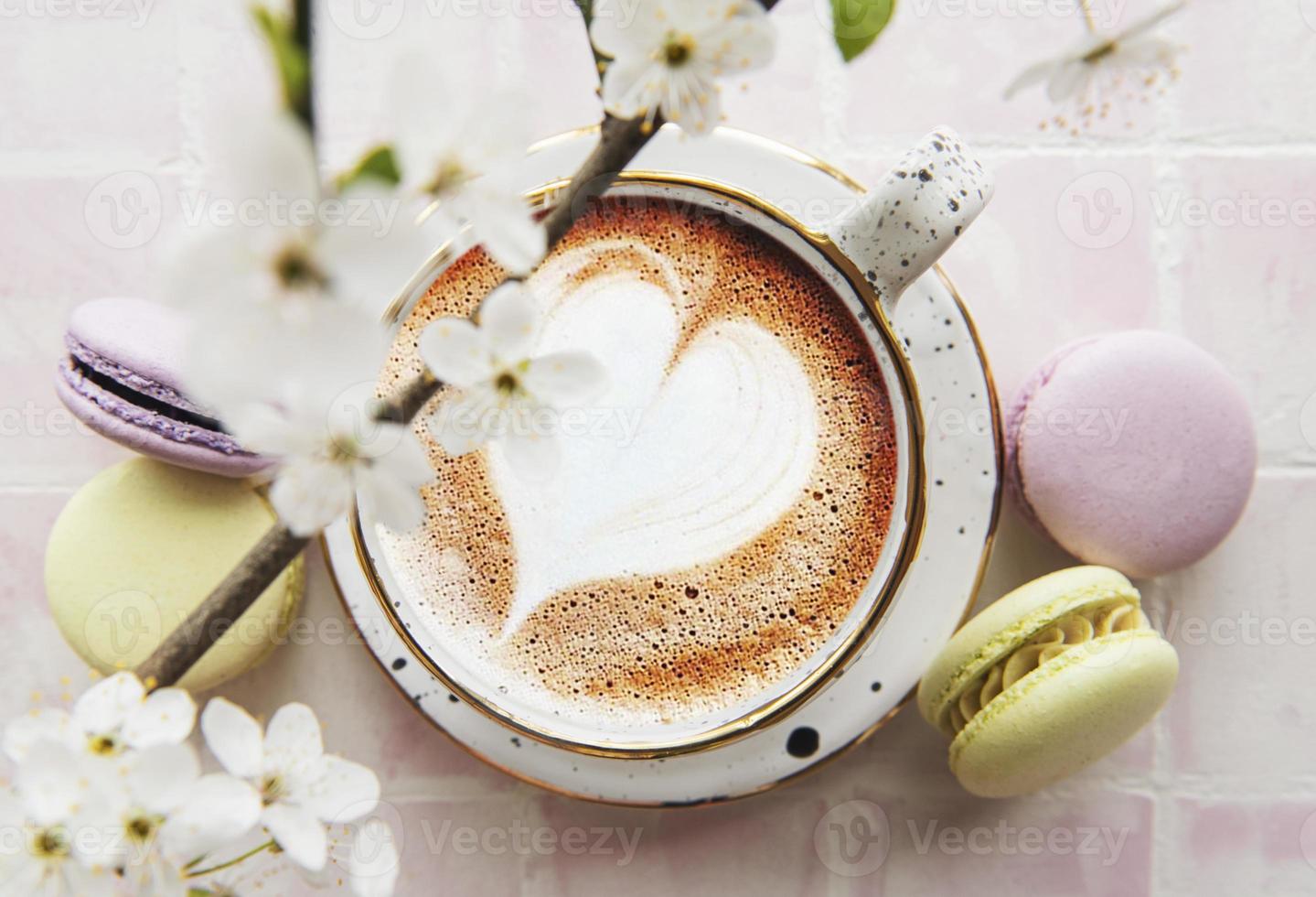 Kaffee mit herzförmigem Muster und süße Makronen-Desserts foto