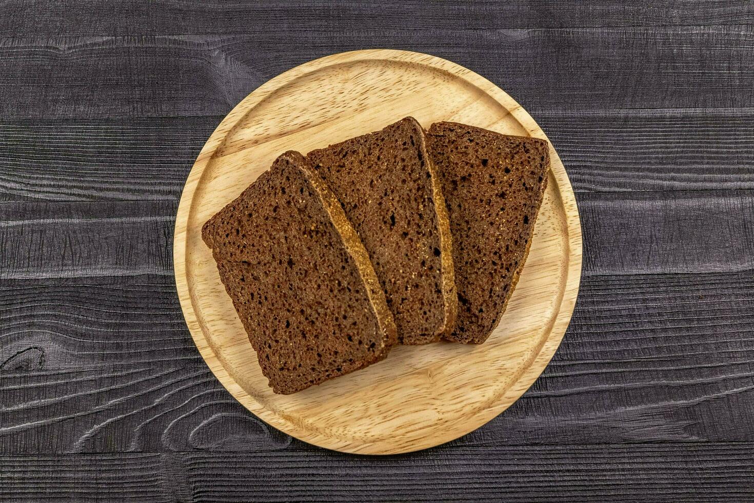 Stücke von Roggen Mehl schwarz Brot auf ein hölzern Portion Teller und bl foto
