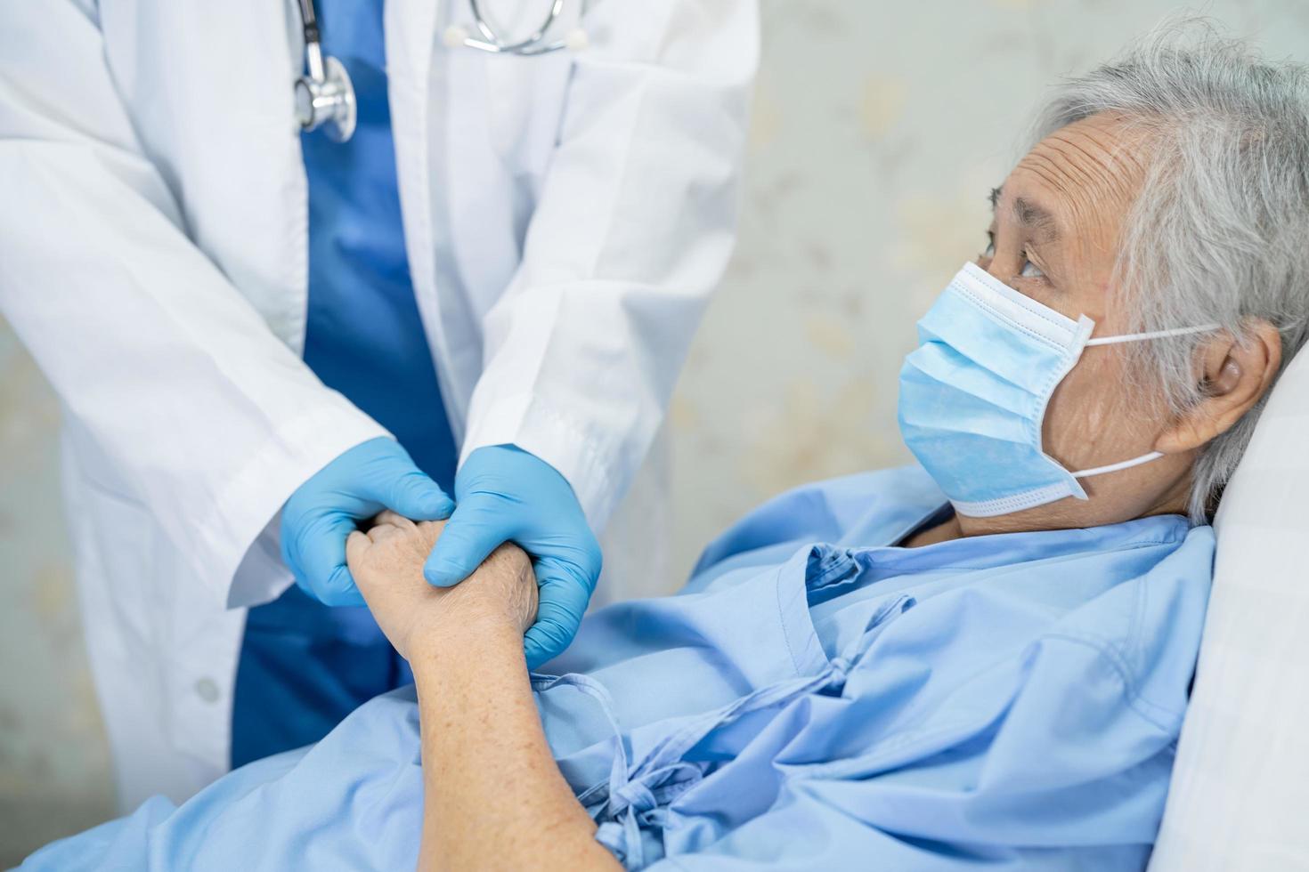 Arzt, der im Krankenhaus einen asiatischen Senior oder eine ältere Frau mit einer Gesichtsmaske überprüft, um die Infektion mit Covid 19 Coronavirus zu schützen foto