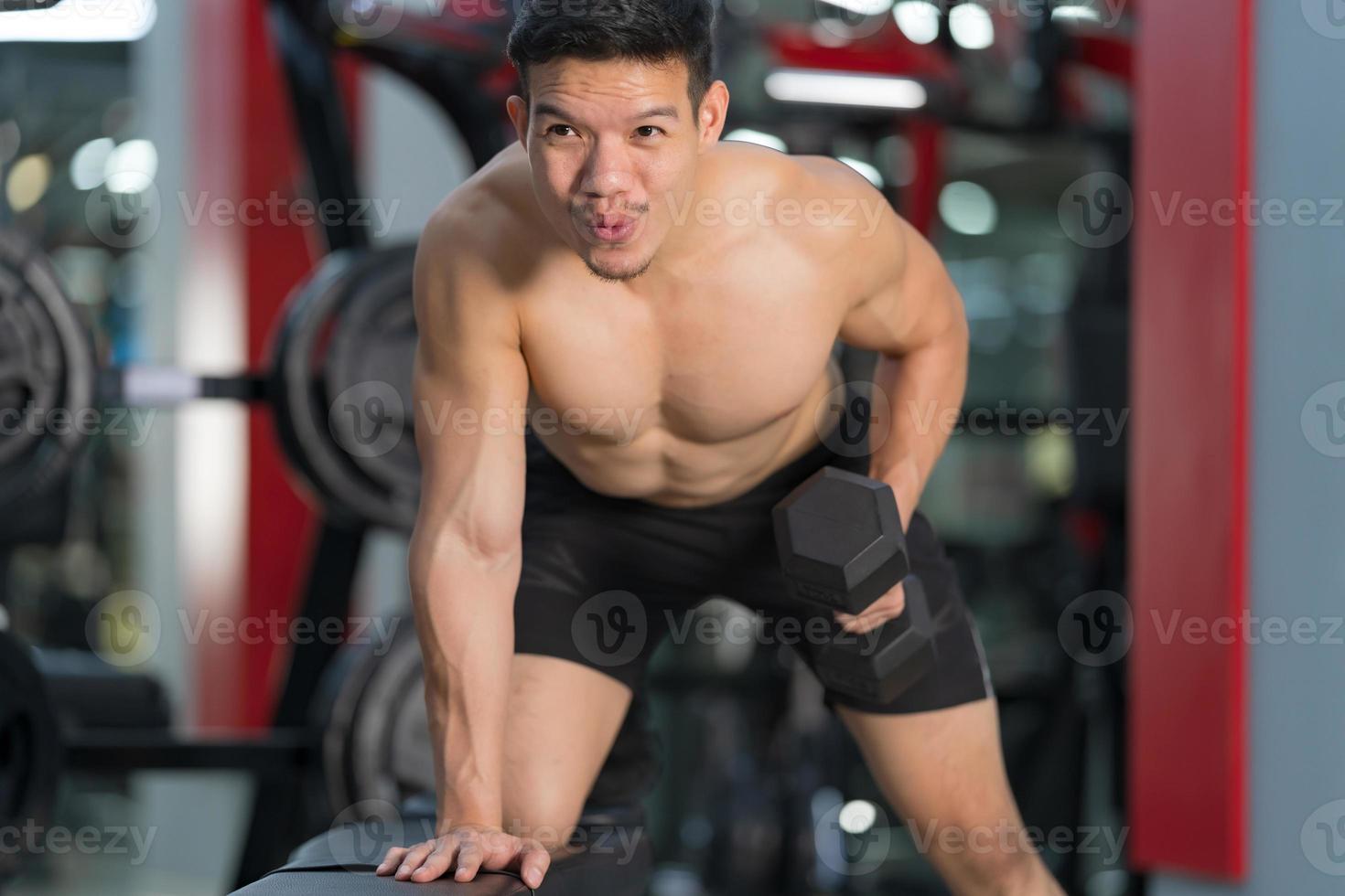 sportlicher Mann, der mit Hantel im Fitnessstudio trainiert foto